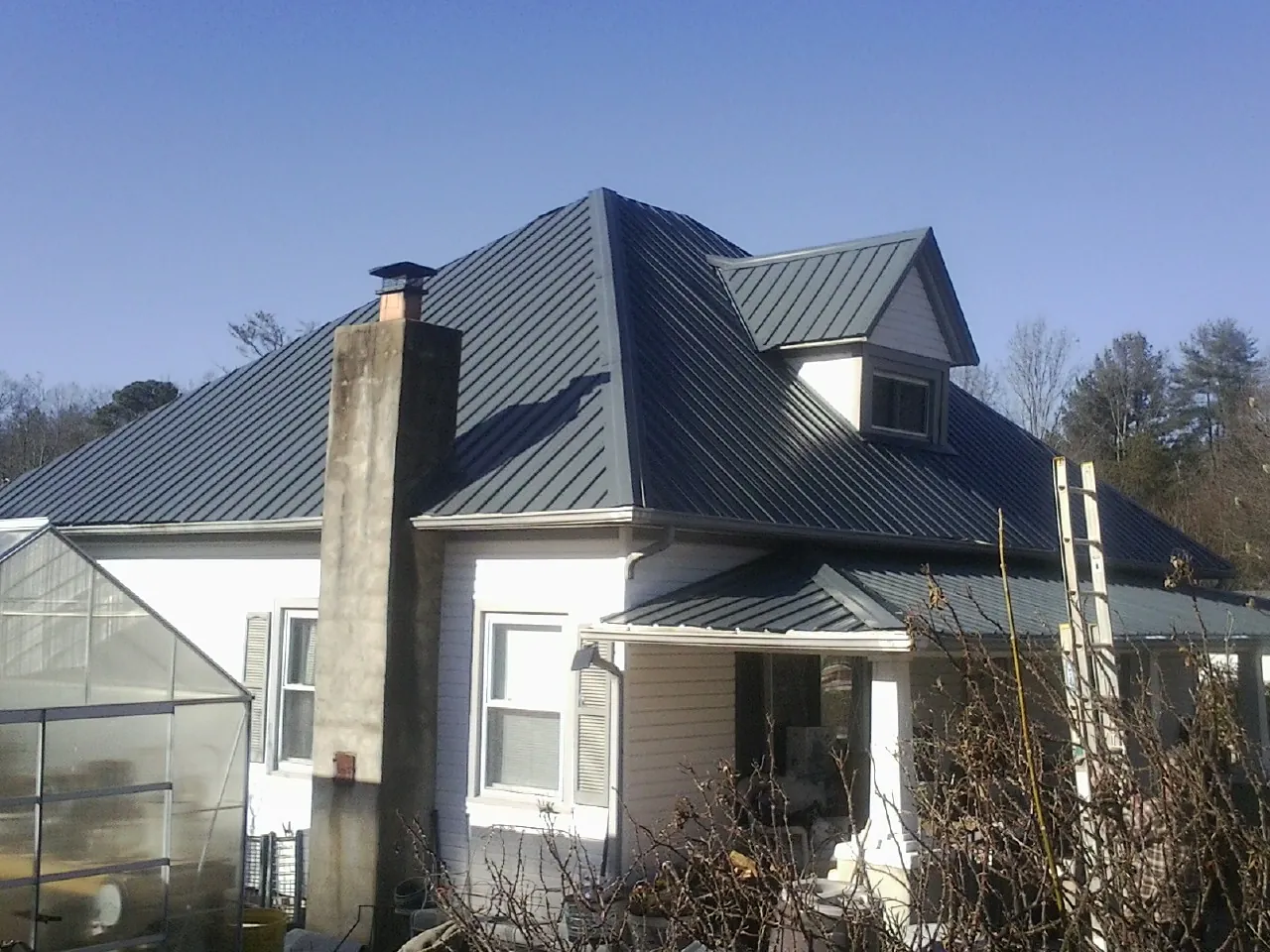 Dark blue standing seam metal roof on a white farmhouse with dormer — Slate & Tile Roof Repair by Roofing Brothers in Fombell