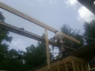 Carpenter setting a ridge beam over a new addition frame — Ice Dam Removal by Roofing Brothers in Fombell