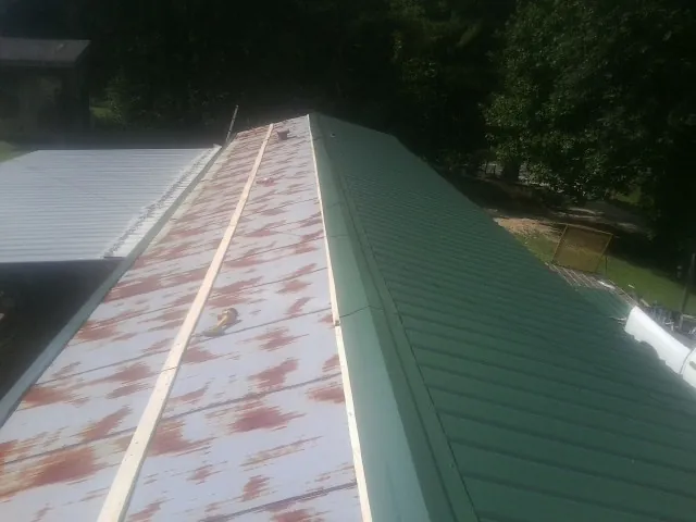 Old rusted panels beside newly installed green metal roofing — Wind Damage Roof Repair by Roofing Brothers in Fombell