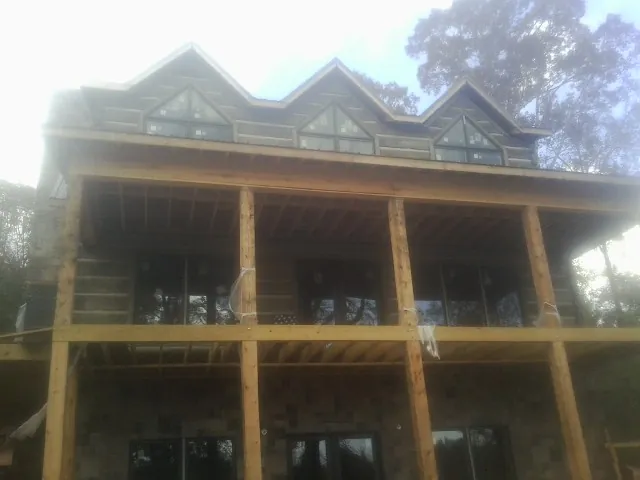 Dormers and porch framing on a large log home under construction — Roof Coating work by our crew in Fombell