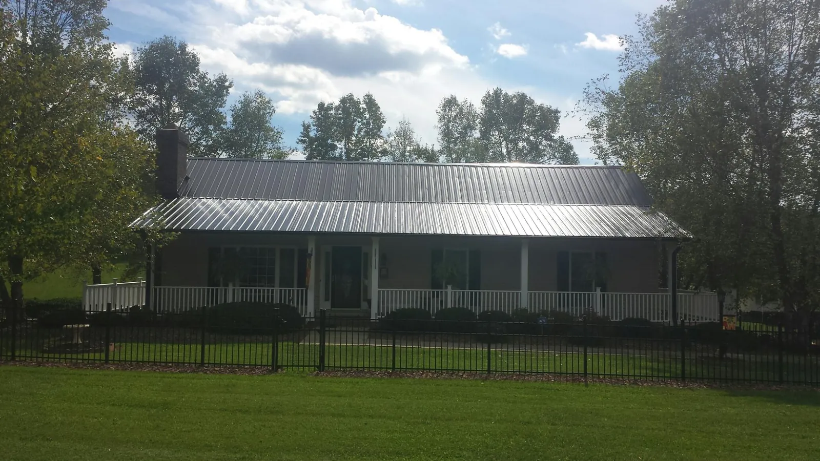 Gray metal roof on a brick ranch with a full width front porch — Gutter Guard Installation work by our crew in Fombell