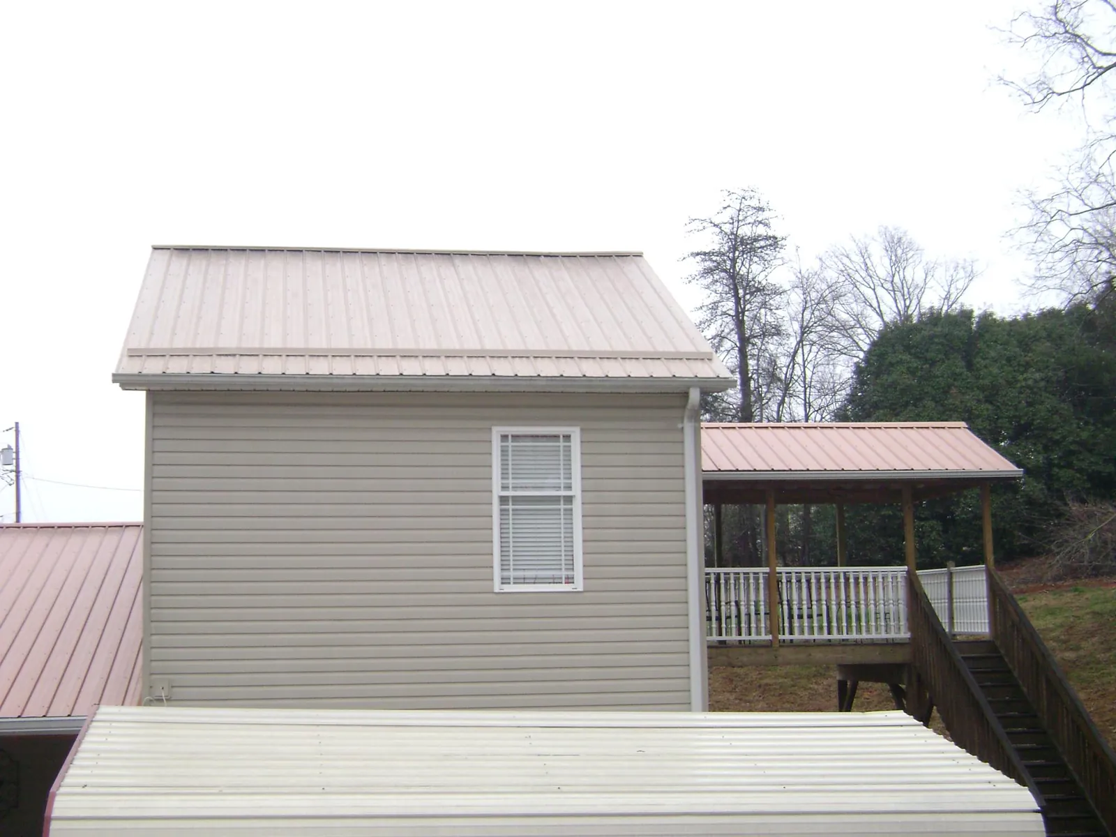Tan metal roofs on a two story addition and attached porch, from a Roof Replacement job in Fombell