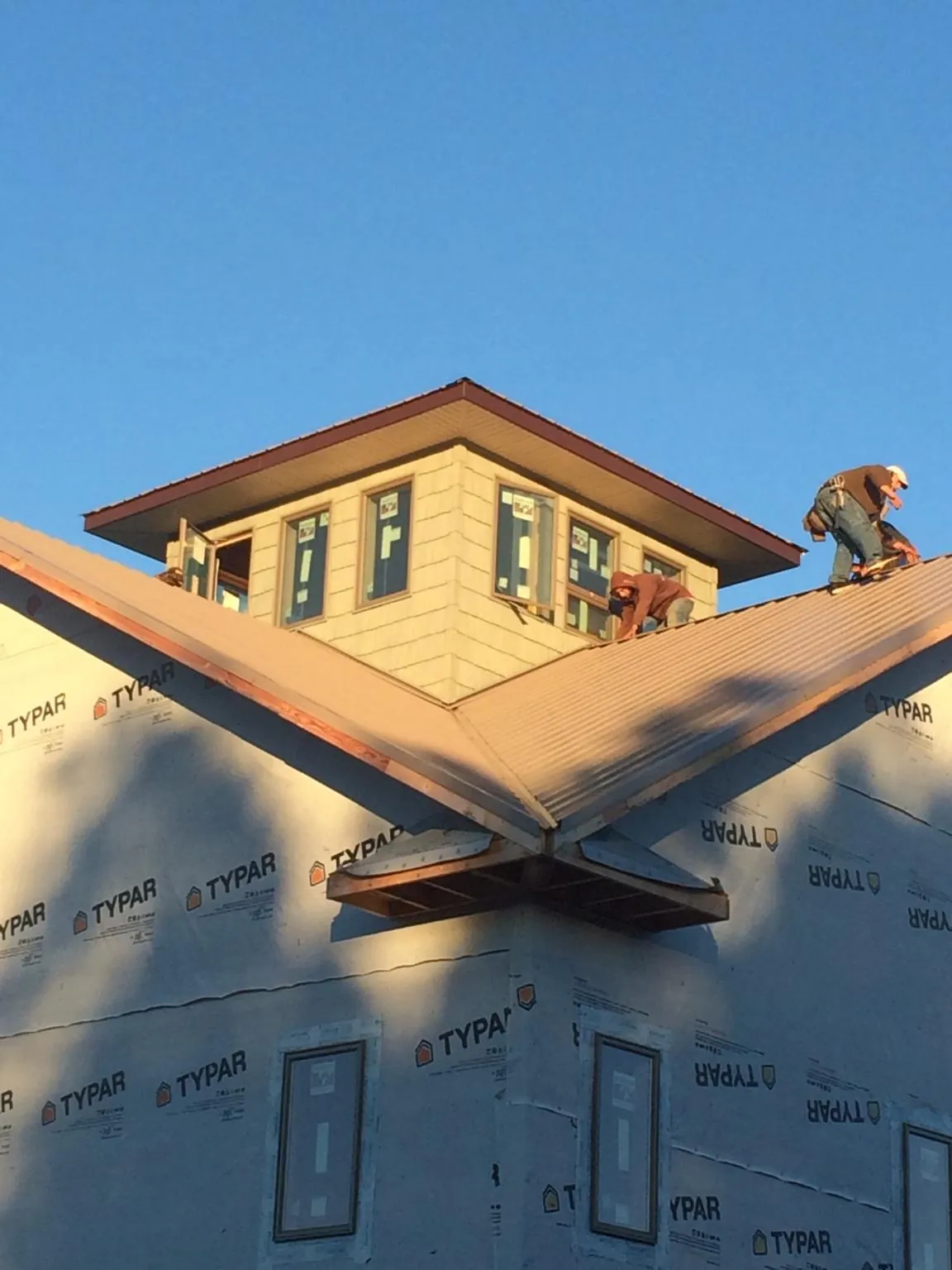 Roofers working around a rooftop cupola on a new metal roof at sunset — Roof Waterproofing in Fombell by Roofing Brothers